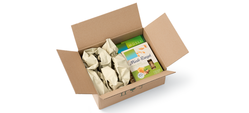 Una scatola di cartone contenente una confezione di muesli e delle strisce d’imbottitura di carta prodotte con carta d’erba