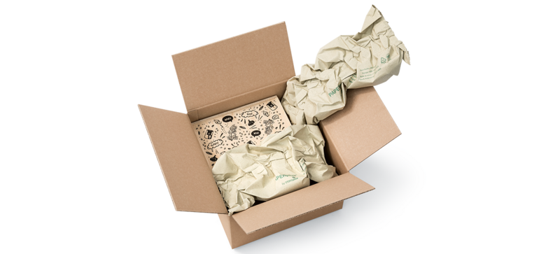 Una scatola di cartone contenente una scatola di legno e delle strisce d’imbottitura di carta prodotte con carta d’erba