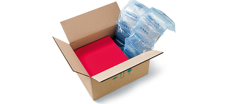 Una scatola di cartone contenente una scatola rossa e delle imbottiture d’aria 100% Recycled