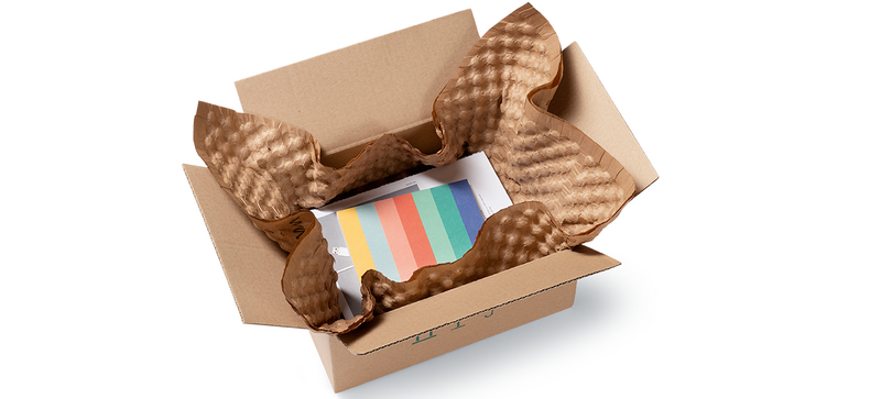 Una scatola di cartone con prodotti e fogli di pluriball di carta marroni